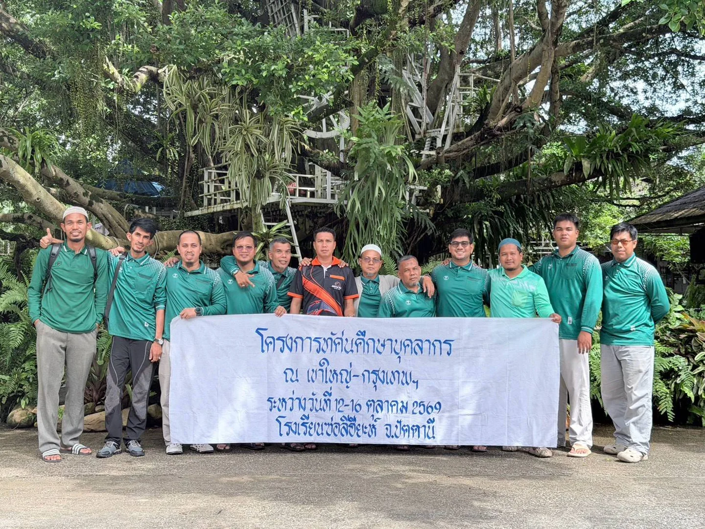 คณะเดินทางสวมเสื้อสีเขียวถ่ายภาพร่วมกัน